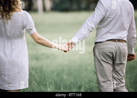 Vista posteriore. felice coppia camminare sull'erba Foto Stock