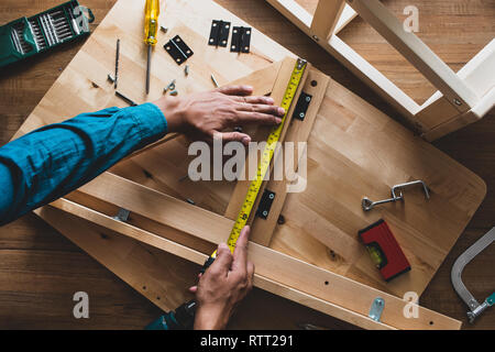 Gruppo uomo mobili in legno,il fissaggio o la riparazione di casa con nastro adesivo giallo misure.vista superiore Foto Stock