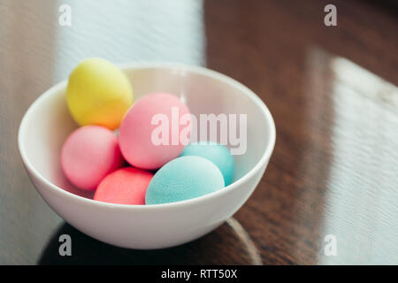 Le uova di pasqua con colori pastello collocato nel recipiente in bianco su sfondo scuro, close up Foto Stock