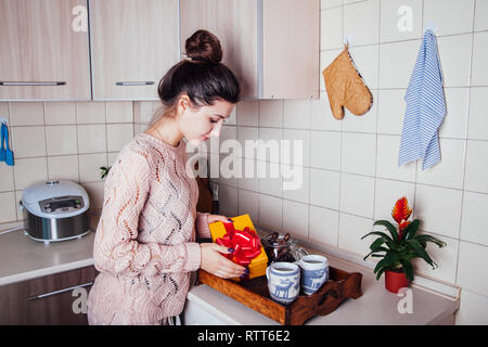La donna prepara una colazione romantica e un regalo per il suo uomo sulla Valntines giorno in cucina Foto Stock