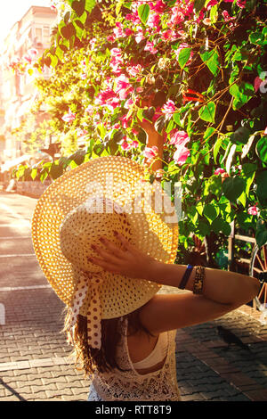 Giovane viaggiatore donna camminare nel giardino estivo e profumati fiori di bouganville al tramonto. Concetto di vacanza Foto Stock