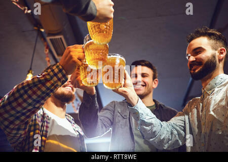 Giovani clink bicchieri di birra in un bar. Foto Stock