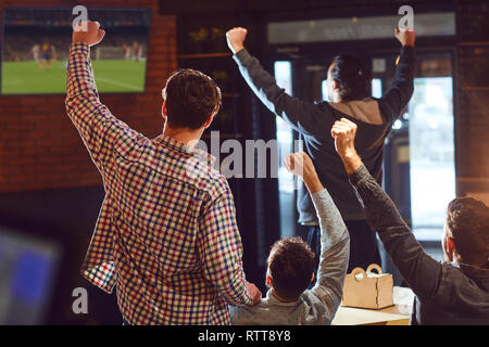 I giovani a guardare il calcio in TV nella barra. Foto Stock