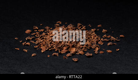 Il cioccolato grattugiato. Heap di massa di cioccolato isolato su sfondo nero, primo piano Foto Stock