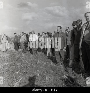 1967, vita di paese.....Funzionari e spectactors locale in piedi in un campo arato in una fattoria a guardare a giovani agricoltori match di aratura, Inghilterra, Regno Unito. Foto Stock