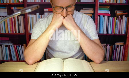 Lettura di Uomo alla scrivania con lampada. Foto Stock