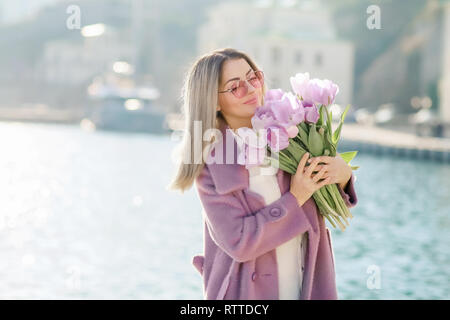 Bella donna felice con i capelli dritti tenendo un bouquet di tulipani rosa primavera una giornata di sole. Foto Stock