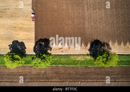 Immagine aerea che mostra le operazioni di aratura di un grande campo da un trattore rosso nella primavera del sole di Clyde Valley area della South Lanarkshire.. Foto Stock