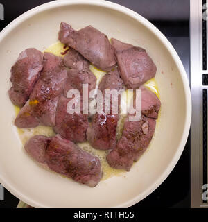 La carne di cervo è la frittura in una padella con il burro Foto Stock