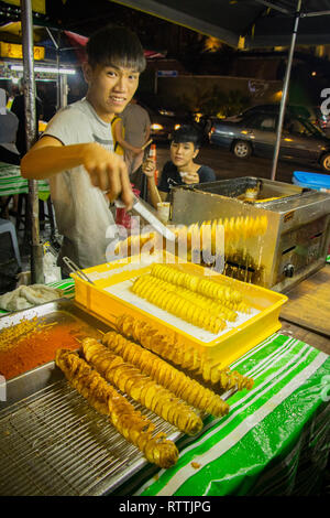 Giovani trader sorridendo come lui vende alimenti fritti in Connaught mercato notturno, Cheras, Kuala Lumpur, Malesia Foto Stock