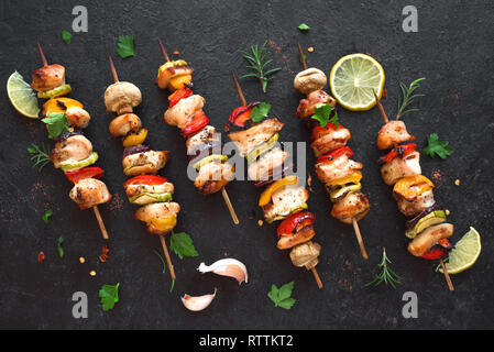 Verdure grigliate e spiedini di pollo con peperoni, zucchine, cipolla e funghi su sfondo nero, vista dall'alto, copia dello spazio. La carne e le verdure Foto Stock