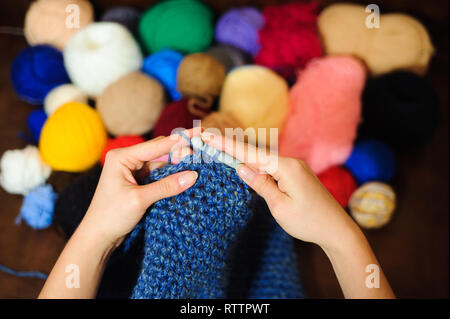 Filati colorati impilati in una serie di colori. Le sfere e le matasse di filo colorato per maglieria. Una donna che va a lavorare a maglia. Foto Stock