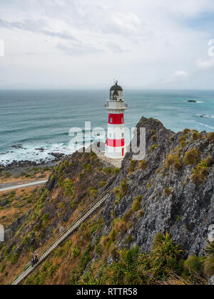 Guardando verso il basso su 2 persone, arrampicate ripide lunga fila di scale, fino a Cape Palliser faro, Palliser Bay, Wairarapa, Nuova Zelanda Foto Stock