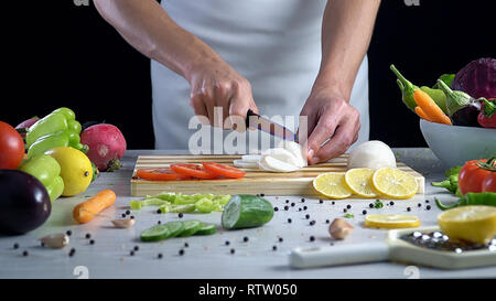 L uomo è il taglio di vegetali in cucina, affettare Rafano nero Foto Stock