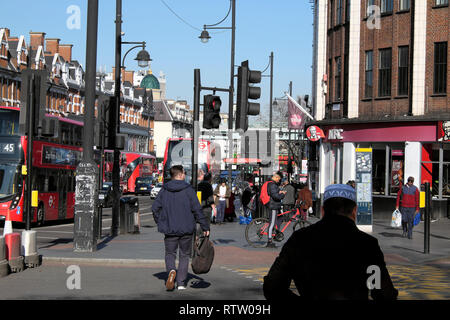 La gente camminare lungo la trafficata strada di Brixton attraversare la strada al semaforo e autobus di Brixton, Borough di Lambeth, South London UK KATHY DEWITT Foto Stock