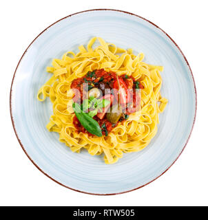 Tagliatelle con salsa di pomodoro e olive, capern e le foglie di basilico sul rustico argilla smaltate piastra - isolato su sfondo bianco Foto Stock