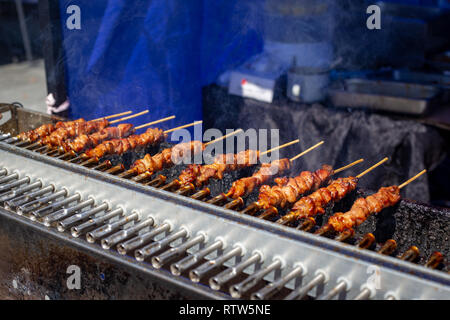 Christchurch Square, Christchurch, Nuova Zelanda, 2 Marzo 2019: spiedini di carne di maiale o il barbecue spiedini di essere preparato per la vendita in un mercato alimentare per le Filippine giorno Foto Stock