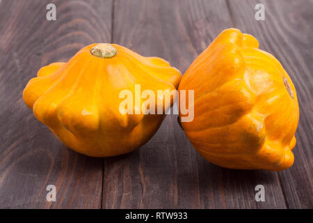 Due giallo pattypan squash al buio su un tavolo di legno Foto Stock