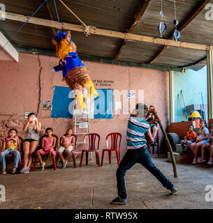 Giovane ragazzo latino swinging a pinata a Guatemala festa di compleanno Foto Stock