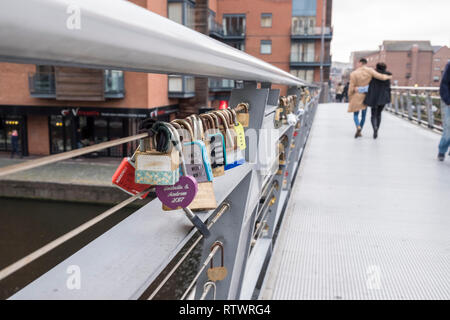 Abbracciando giovane a piedi passato Lovelocks o amore blocca bloccato su di un ponte a Birmingham, Inghilterra, GB, UK. Foto Stock