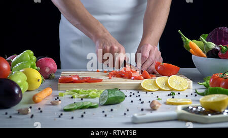 L uomo è il taglio di vegetali in cucina, affettare il pomodoro Foto Stock