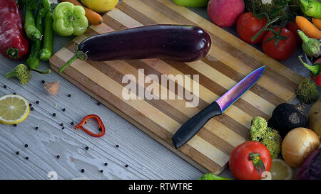 L uomo è il taglio di vegetali in cucina, affettare la melanzana Foto Stock
