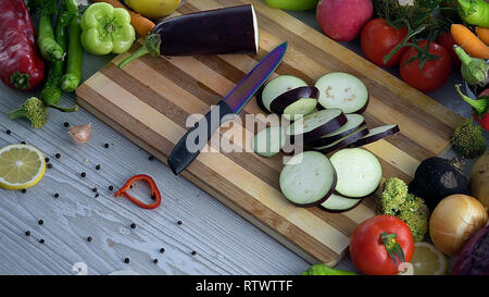 L uomo è il taglio di vegetali in cucina, affettare la melanzana Foto Stock