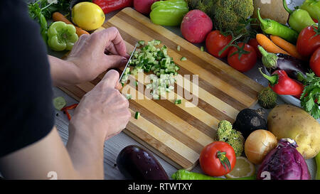 L uomo è il taglio di vegetali in cucina, Affettare cetrioli Foto Stock