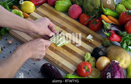 L uomo è il taglio di vegetali in cucina, affettare il peperone verde Foto Stock