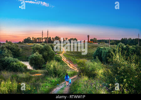 Una donna con un bambino a camminare su una strada rurale Foto Stock