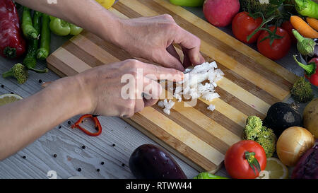 L uomo è il taglio di vegetali in cucina, affettare la cipolla Foto Stock