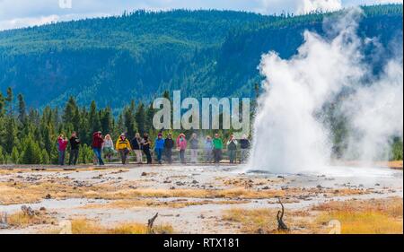 I turisti a guardare l'eruzione di Jewel Geyser, sabbia nera e bacino bacino di biscotto, il Parco Nazionale di Yellowstone, Wyoming USA Foto Stock