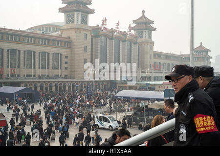 Due uomini della sicurezza guardare la folla nella stazione ferroviaria di Pechino. La Cina vieta 23m dall'acquisto di biglietti di viaggio come parte del 'sociale' di credito sistema 03-Mar-2019 Foto Stock