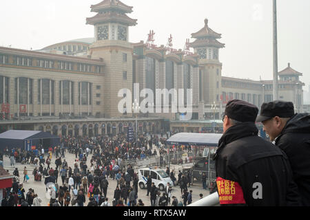Due uomini della sicurezza guardare la folla nella stazione ferroviaria di Pechino. La Cina vieta 23m dall'acquisto di biglietti di viaggio come parte del 'sociale' di credito sistema 03-Mar-2019 Foto Stock