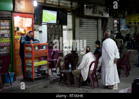 Gruppo di uomini guardando la partita di calcio in un Cairo backstreet Foto Stock