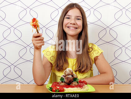 Felice ragazza adolescente con polpette e spaghetti per il pranzo Foto Stock