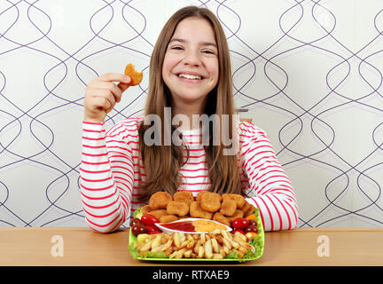 Felice ragazza adolescente con gustosi pepite di pollo e patatine fritte Foto Stock