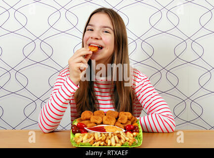 Fame ragazza adolescente mangia gustosi bocconcini di pollo Foto Stock