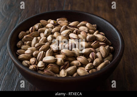 I pistacchi con guscio in ciotola di legno. Spuntini organico. Foto Stock