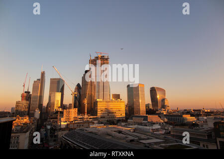 Un drammatico City of London skyline con gli alti edifici immersi nella luce dorata Foto Stock