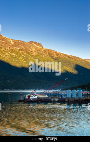 Settembre 15, 2018 - Skagway AK: Broadway Dock cargo industriale wharf con rimorchiatore a traino e gru a sunrise. Foto Stock