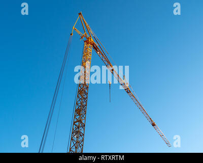 Grande, giallo gru da cantiere contro un luminoso cielo blu Foto Stock