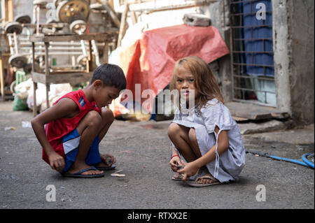 Due giovani figli Filippino giocare un gioco all'interno di una delle baraccopoli di Cebu, Filippine Foto Stock