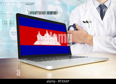 Cambogia sistema sanitario in tema tech. Bandiera cambogiana sullo schermo del computer. Dottore in piedi con uno stetoscopio in ospedale. E Cryptocurrency Blockcha Foto Stock