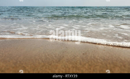 Angolo basso / livello di massa foto di sabbia bagnata sulla spiaggia, mare sullo sfondo. Foto Stock