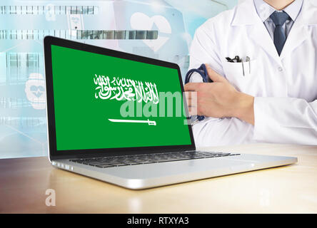 Arabia Saudita sistema sanitario in tema tech. Arabia bandiera sullo schermo del computer. Dottore in piedi con uno stetoscopio in ospedale. E Cryptocurrency Blockcha Foto Stock