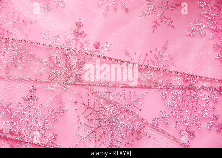 Un abstract texture di sfondo close up dettaglio in un Natale nastro rosa glitter con i fiocchi di neve Foto Stock