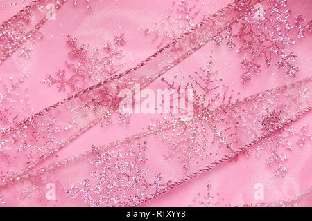 Un abstract texture di sfondo close up dettaglio in un Natale nastro rosa glitter con i fiocchi di neve Foto Stock