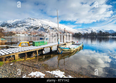 Barche sulle rive innevate di Ullswater nel Lake District in Cumbria Foto Stock