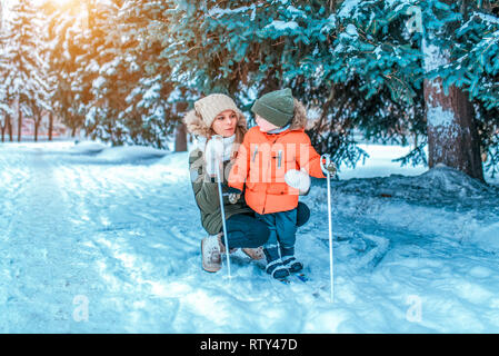 Giovane e bella madre, insegna il figlio di Little Boy 2-4 anni, per stare in inverno sci per bambini. Spazio libero per il testo. Lezioni infanzia sport Foto Stock